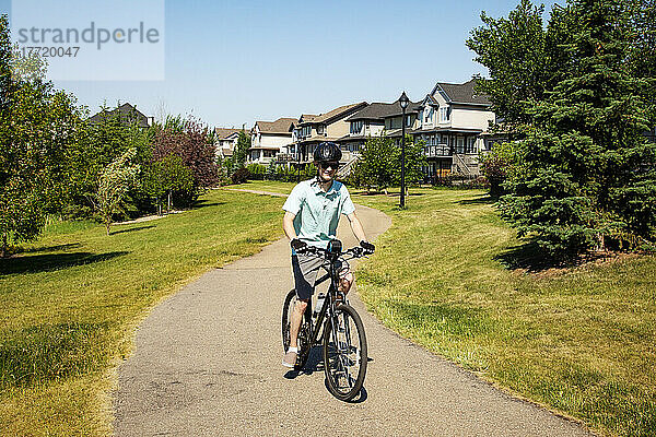 Junger Mann fährt mit seinem Fahrrad einen Weg in einem Wohnpark hinunter; Edmonton  Alberta  Kanada