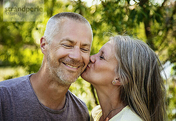 Porträt eines reifen Paares im Freien mit einer Frau  die die Wange ihres Mannes küsst; Edmonton  Alberta  Kanada