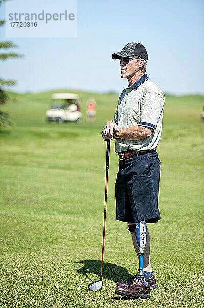 Amputierter mit Beinprothese steht mit Golfschläger auf dem Golfplatz; Okotoks  Alberta  Kanada