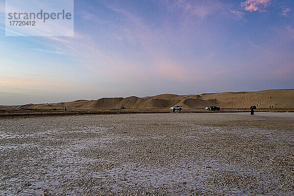 Touristen und Fahrzeuge in einer Wüstenlandschaft bei Sonnenuntergang; Abu Dhabi  Vereinigte Arabische Emirate