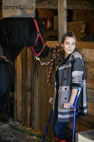 Ein junges Mädchen mit Cerebralparese mit einem Pferd in einer Scheune während einer Hippotherapie-Sitzung; Westlock  Alberta  Kanada