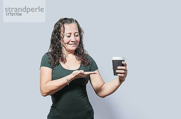 Lächelnde Person mit Kaffee auf isoliertem Hintergrund  Frau zeigt auf Einwegbecher mit Kaffee auf isoliertem Hintergrund  Eine Frau zeigt mit Blick auf Einwegbecher mit Kaffee