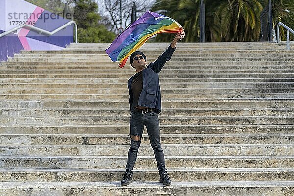 Lating Homosexuell Männchen whit Make-up auf tragen modische Hut hält lgbt Flagge. Konzept der Freiheit und Toleranz