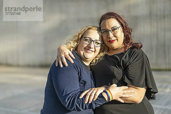 Ein Paar lesbischer Fraün  die sich in einem Park umarmen und in die Kamera schauen