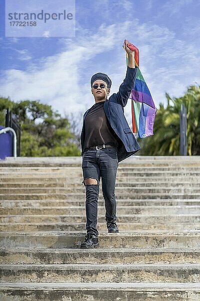 Lating Homosexuell Männchen whit Make-up auf tragen modische Hut hält lgbt Flagge. Konzept der Freiheit und Toleranz