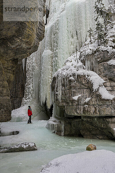Ein Mann im roten Mantel stand bei winterlichen Bedingungen im Maligne Canyon  Jasper-Nationalpark  UNESCO-Weltkulturerbe  Alberta  Kanada  Nordamerika