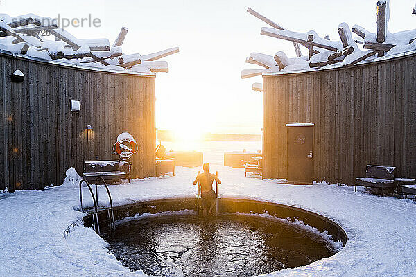 Mann genießt den Sonnenuntergang  während er ein kaltes Bad im Pool des Arctic Bath Spa and Wellness Hotel  Harads  Lappland  Schweden  Skandinavien  Europa nimmt