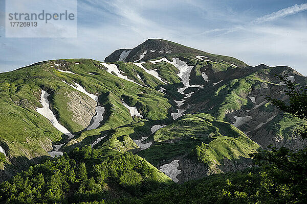 Cusna-Berg mit üppigem grünem Gras und etwas schmelzender Schneezone  Emilia Romagna  Italien  Europa