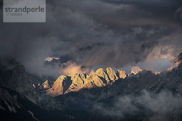 Lichtstrahlen treffen bei Sonnenuntergang auf die Berggipfel der Dolomiten  umgeben von niedrigen Wolken und Nebel  Cortina d'Ampezzo  Dolomiten  Venetien  Italien  Europa