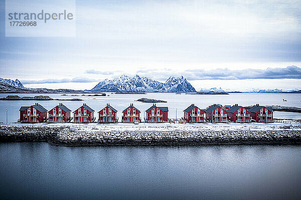 Luftaufnahme von roten Rorbu-Hütten in einer Reihe inmitten des kalten Meeres im Winter  Svolvaer  Kreis Nordland  Lofoten  Norwegen  Skandinavien  Europa