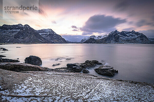 Wolken im Morgengrauen über dem kalten Meer und dem schneebedeckten Strand von Vareid  Flakstad  Kreis Nordland  Lofoten  Norwegen  Skandinavien  Europa