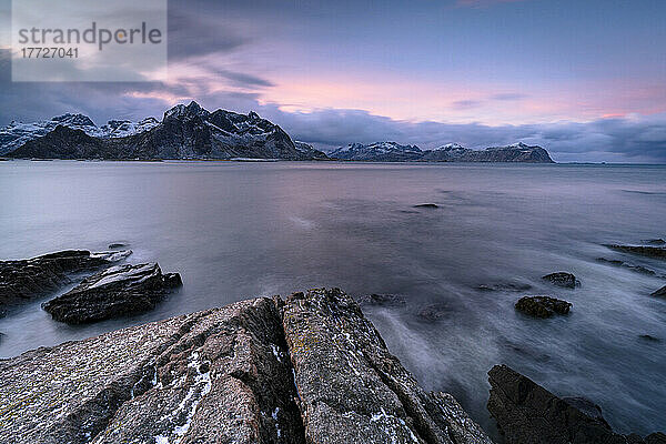 Rosa arktischer Sonnenaufgang über schneebedeckten Bergen und gefrorenem Fjord  Vareid  Flakstad  Nordland  Lofoten  Norwegen  Skandinavien  Europa