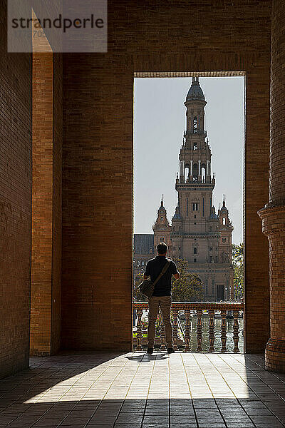 Mann genießt die Aussicht auf die Plaza de Espana  eingerahmt durch einen Torbogen  Sevilla  Andalusien  Spanien  Europa