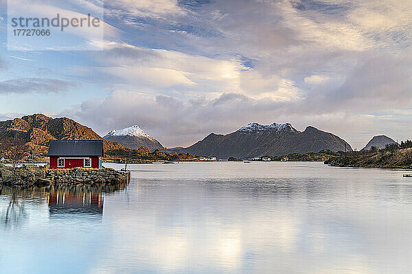 Isolierte Fischerhütte spiegelt sich im Morgengrauen im Meer  Ballstad  Vestvagoy  Kreis Nordland  Lofoten  Norwegen  Skandinavien  Europa