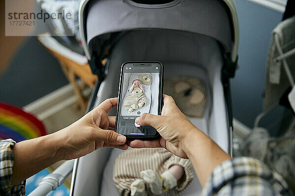Mutter fotografiert 3 Monate alten Jungen im Kinderwagen mit ihrem Smartphone