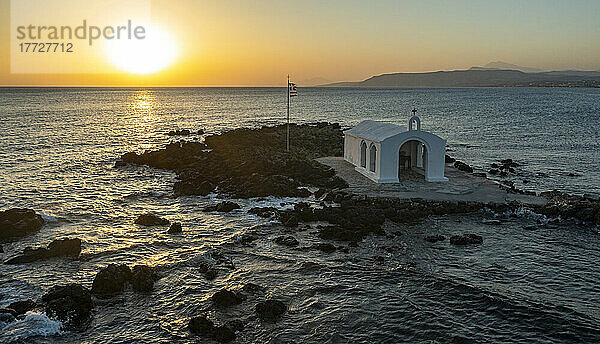 Luftaufnahme der kleinen Kirche von Agios Nikolaos auf einer Insel am rauen Meer bei Sonnenaufgang  Georgioupolis  Insel Kreta  griechische Inseln  Griechenland  Europa
