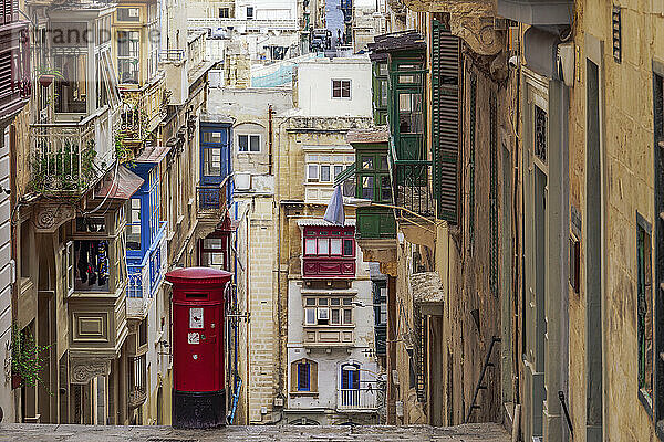 Typische Straßenszene einer Gasse mit traditionellen Häusern  bunten Balkonen und rotem Briefkasten  Valletta  Malta  Europa