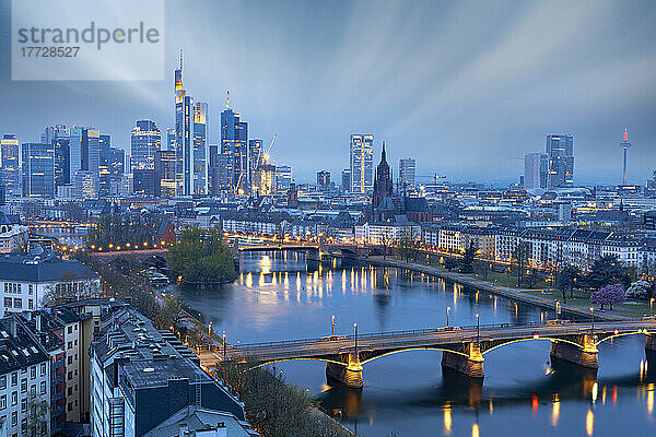 Langzeitbelichtung von Wolken in der Abenddämmerung über der beleuchteten Skyline der Stadt und der Ignatz-Bubis-Brücke  Frankfurt am Main  Hessen  Deutschland Europa