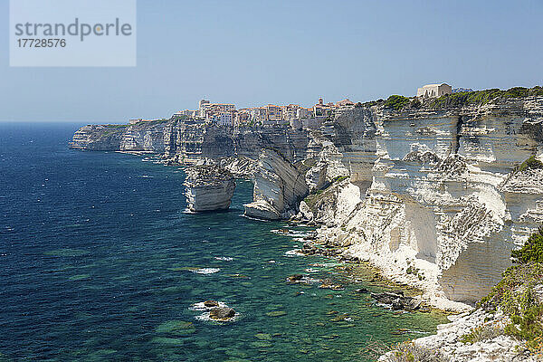 Blick über die felsige Bucht entlang schroffer Kalksteinklippen bis zur entfernten Zitadelle  Bonifacio  Corse-du-Sud  Korsika  Frankreich  Mittelmeer  Europa