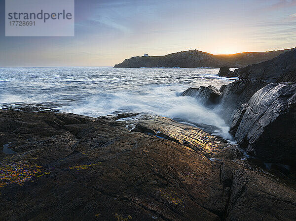 Sonnenaufgang über einer Bucht mit Wellen  die durch die Kamera kommen  Bretagne  Frankreich  Europa