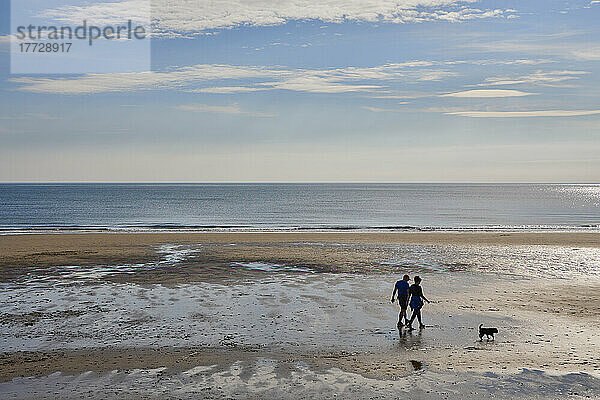 Paar geht mit Hund am Strand von North Bay  Scarborough  Yorkshire  England  Vereinigtes Königreich  Europa