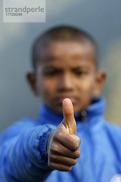 Rehabilitation center for street children  portrait of boy giving thumbs up  positive sign of agreement and like  Nepal  Asia