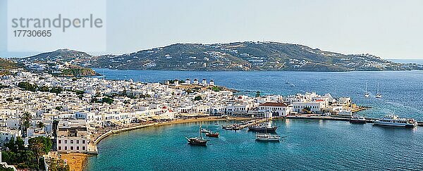 Blick auf Mykonos Stadt Griechisch touristischen Urlaubsziel mit berühmten Windmühlen  und Hafen mit Booten und Yachten bei Sonnenuntergang  Mykonos  Kykladen-Inseln  Griechenland. Mit horizontalem Kameraschwenk