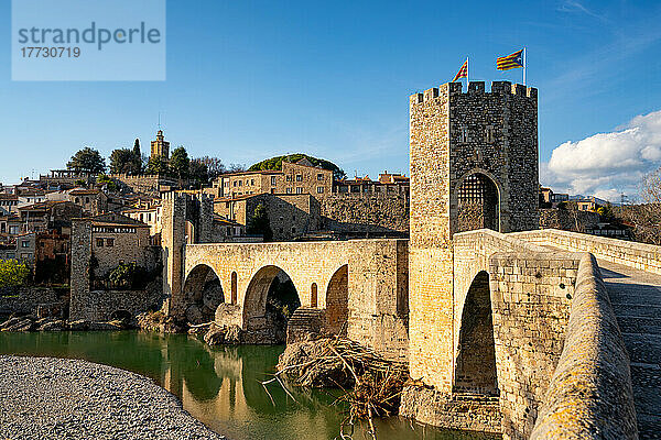 Besalu historische mittelalterliche Stadt mit katalanischen Flaggen auf dem steinernen Brückenturm über den Fluss El Fluvia  Besalu  Katalonien  Spanien  Europa