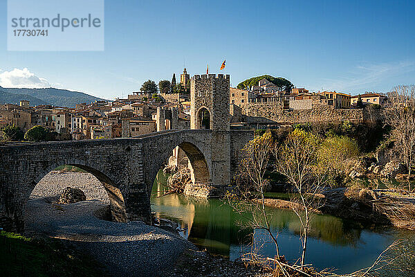 Besalu historische mittelalterliche Stadt mit katalanischen Flaggen auf dem steinernen Brückenturm über den Fluss El Fluvia  Besalu  Katalonien  Spanien  Europa
