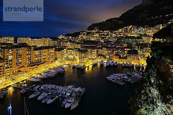 Luftaufnahme des Hafens von Monaco Monte Carlo und der beleuchteten Skyline der Stadt in der abendlichen blauen Dämmerung. Monaco Hafen Nachtansicht mit luxuriösen Yachten