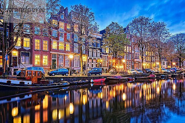 Nachtansicht der Stadt Amsterdam mit Grachten  Booten und mittelalterlichen Häusern in der Abenddämmerung beleuchtet. Amsterdam  Niederlande  Europa