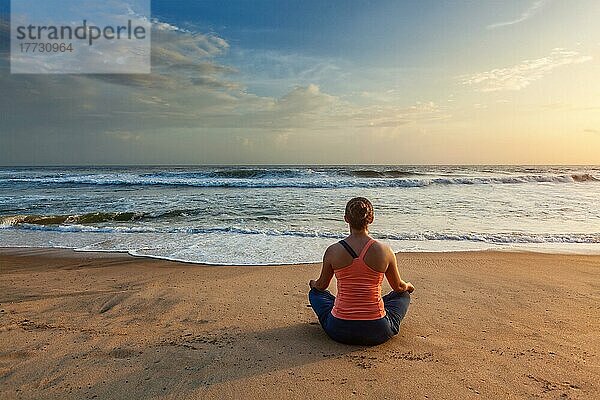 Frau macht Yoga  meditiert und entspannt in Padmasana Lotus Asana Pose mit Kinn Mudra im Freien am tropischen Strand bei Sonnenuntergang