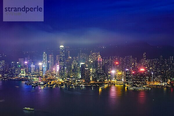 Luftaufnahme der beleuchteten Skyline von Hongkong mit den Wolkenkratzern der Innenstadt über dem Victoria Harbour in den Abendstunden. Hongkong  China  Asien