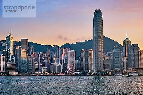 Hong Kong Skyline Stadtbild Innenstadt Wolkenkratzer über Victoria Harbour am Abend mit Dschunke Touristenfähre Boot auf Sonnenuntergang mit dramatischen Himmel. Hongkong  China  Asien