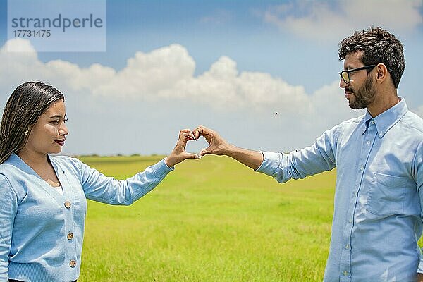 Glückliches Paar  das mit seinen Händen eine Herzform bildet  verliebtes Paar auf dem Feld  schönes Paar auf dem Feld