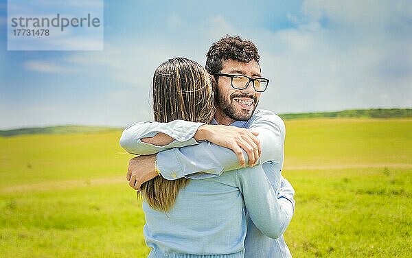 Ein Mann umarmt seine Frau in einem schönen Feld  Nahaufnahme eines glücklichen Paares  das sich im Feld umarmt  ein junges verliebtes Paar  das sich im grünen Feld umarmt