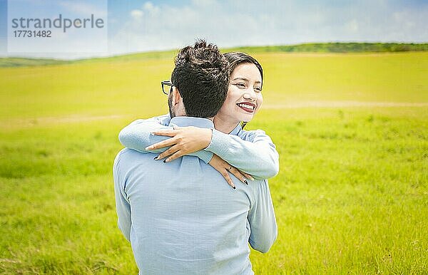Nahaufnahme eines glücklichen Paares  das sich auf einem Feld umarmt  ein junges verliebtes Paar  das sich auf einer grünen Wiese umarmt  ein Mann  der seine Frau auf einem schönen Feld umarmt