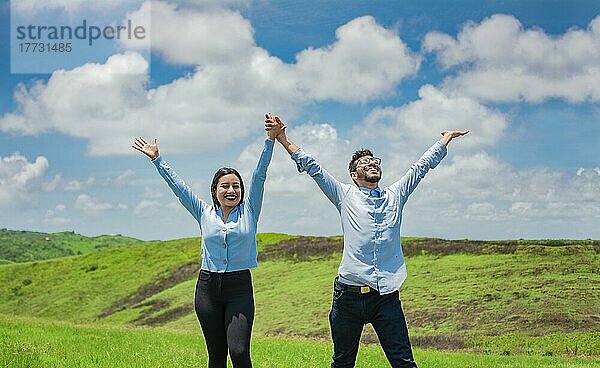 Konzept eines glücklichen und freien Paares auf dem Feld  Paar auf dem Hügel mit zum Himmel erhobenen Händen  Glückliches Paar auf dem Feld  das die Hände in den Himmel hebt