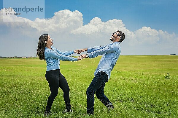 Glückliches Paar  das sich im Kreis auf dem Feld dreht  glückliches junges Paar  das sich auf dem Feld dreht und spielt  junges Paar  das sich auf dem Feld dreht