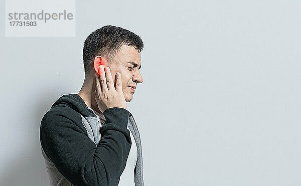 Eine Person mit Otitis und Tinnitus  Person mit Ohrenschmerzen  auf isoliertem Hintergrund  Leidender Mann massiert sein Ohr isoliert