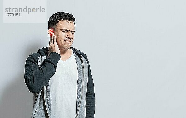Person mit Ohrenschmerzen  auf isoliertem Hintergrund  Leidender Mann massiert sein Ohr isoliert  Eine Person mit Otitis und Tinnitus