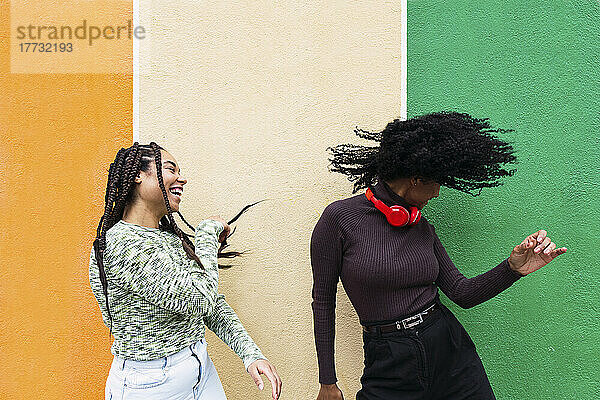 Fröhliche Frauen tanzen gerne vor einer bunten Wand