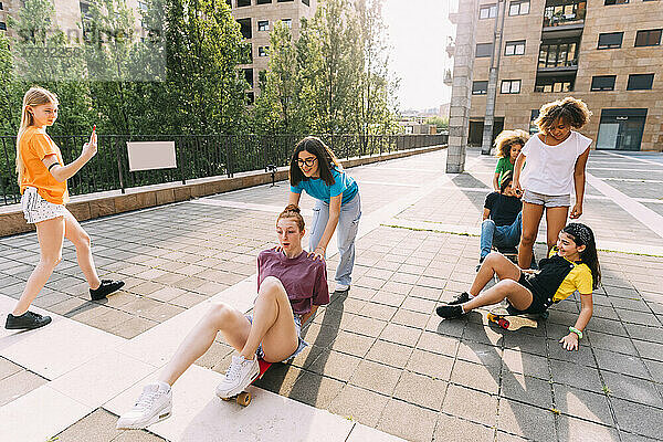 Mädchen fahren Skateboard und genießen es mit Freunden auf dem Parkplatz