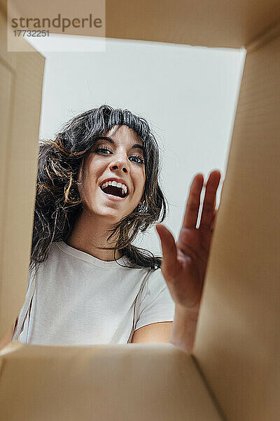 Happy woman with mouth open seen through cardboard box