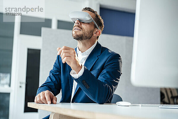 Geschäftsmann mit Virtual-Reality-Headset sitzt am Schreibtisch im Büro