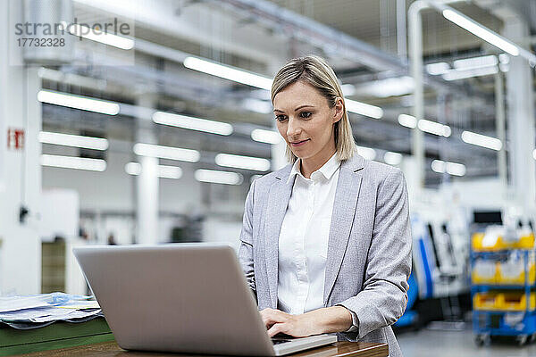 Geschäftsfrau benutzt Laptop in Fabrik