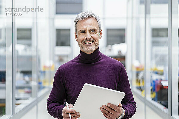 Porträt eines lächelnden Geschäftsmannes mit digitalem Tablet in der Fabrik