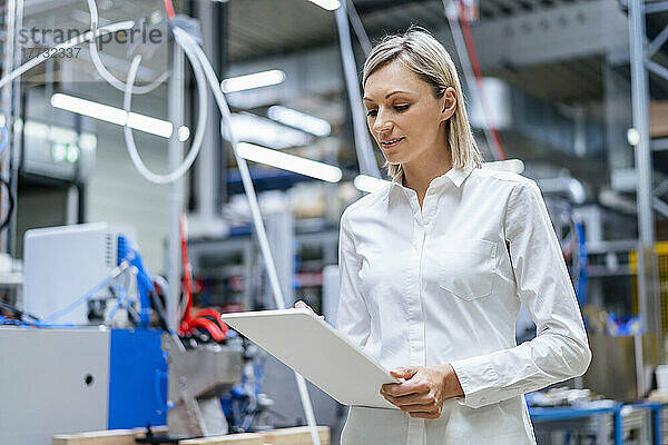 Geschäftsfrau nutzt digitales Tablet in Fabrik