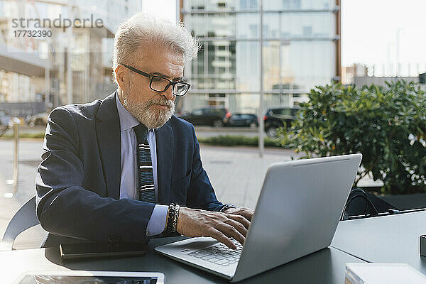 Älterer Geschäftsmann  der draußen am Laptop arbeitet