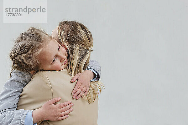Daughter embracing mother against white background